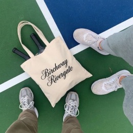 two people standing by a bag on a tennis court